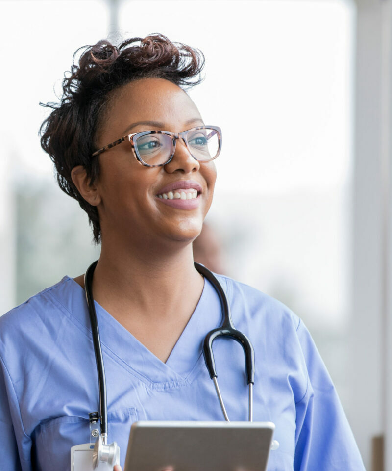 Beautiful nurse smiles while holding digital tablet Beautiful nurse smiles while holding digital tablet